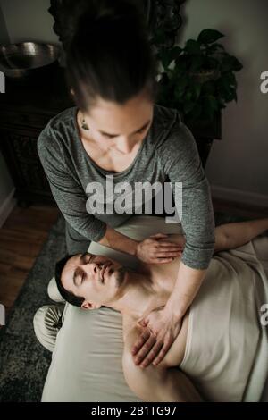 Le client de massage masculin reçoit une pression sur ses épaules de la part du thérapeute Banque D'Images