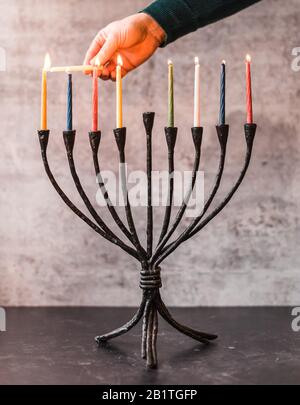Image rognée d'une main éclairant des bougies sur la menorah pour Hanoukkah. Banque D'Images