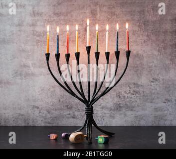 Menorah aux bougies allumées et rêdels sur une table noire pour Hanoukkah. Banque D'Images