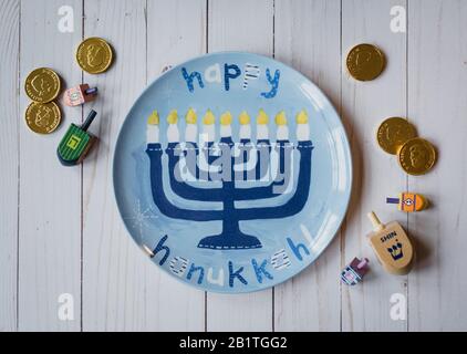 Happy Hanukkah assiette, rêdels et pièces de chocolat sur bois blanc. Banque D'Images