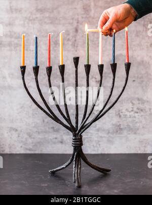 Image rognée d'une main éclairant des bougies sur la menorah pour Hanoukkah. Banque D'Images