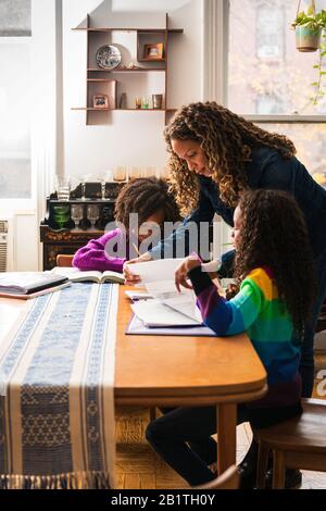 Femme mûre aidant les filles dans des études à la maison Banque D'Images