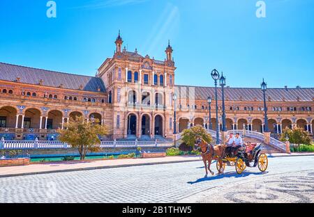 Séville, ESPAGNE - 1er OCTOBRE 2019 : le calèche à cheval se déplace autour de la grande Plaza de Espana le long d'un magnifique bâtiment semi-circulaire avec un ba arqué Banque D'Images