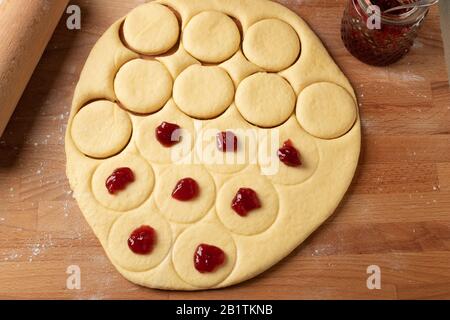 Préparation de beignets faits maison remplis de marmelade de fraises à partir de pâte de levure laminée Banque D'Images