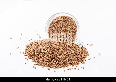 Sarrasin dans une tasse de verre isolée sur fond blanc, régime sain composé de grain sans gluten. Tasse en verre avec sarrasin brut Banque D'Images