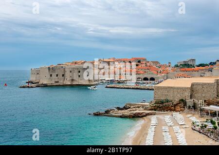 Vue sur les murs de la forteresse de Dubrovnik, la plage et l'eau turquoise. Célèbre plage de Banje avec vue sur les murs de la ville de Dubrovnik et la vieille ville Banque D'Images