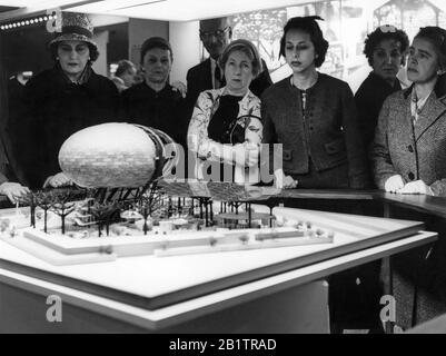 Les femmes se sont rassemblées autour d'un modèle architectural du pavillon IBM avec des arbres en acier fabriqués par l'homme et Ovoid Theatre, conçu par Charles Eames et Eero Saarinen pour la Foire mondiale de New York de 1964. Le modèle du pavillon était exposé au IBM Business Show de Manhattan au New York Coliseum, coïncidant avec l'assemblée annuelle d'IBM Stockholder du 30 avril 1963. Banque D'Images