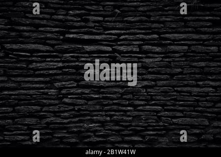 Fond noir. Vieux mur de grès naturel résisté à l'eau. Photo en noir et blanc. Banque D'Images
