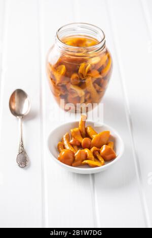 Champignons marinés. Champignons marinés dans un bol sur une table blanche. Banque D'Images