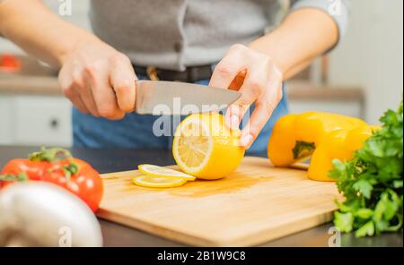 Citron frais. La femme coupe le citron sur la table de cuisine. Banque D'Images