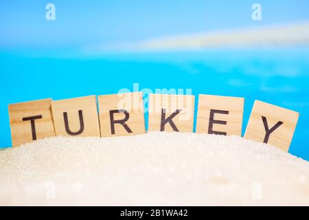 Le mot Turquie sur des blocs de bois dans le sable abstrait avec photo floue d'une plage. L'un des hôtels les plus populaires. Gros plan. Banque D'Images
