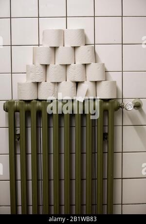 Rouleaux de papier toilette empilés sur un radiateur, dans des toilettes publiques Banque D'Images