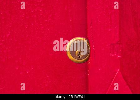 Cadenas en laiton sur une porte en bois peinte en rouge sang. Gros plan. Sécurité, sécurité, concept de sécurité. Banque D'Images