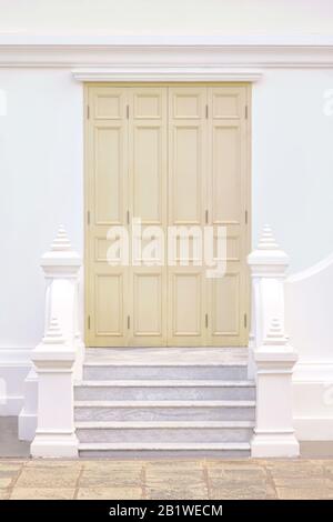 Porte en bois beige pâle peinte sur un mur blanc. Banque D'Images