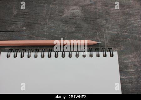 Ouvrez le bloc-notes sur une spirale avec des pages blanches et un crayon sur une table en bois sombre rugueuse. Vue de dessus, espace de copie Banque D'Images