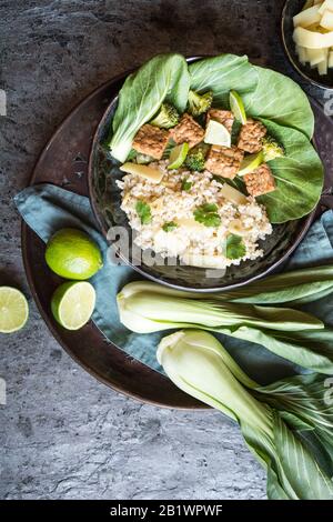 Tempeh avec riz, bok choy, brocoli cuit à la vapeur et pousses de bambou sur une plaque Banque D'Images