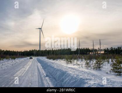 photo du moulin à vent, voiture sur la route droite et peu de pins morts dans la forêt d'hiver, ciel bleu, ensoleillé Banque D'Images