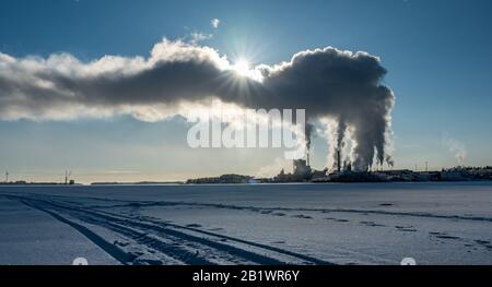 Vue de la centrale électrique de l'usine en hiver avec la vapeur qui s'élève dans un ciel bleu profond, le soleil brille derrière la vapeur, probablement la pollution de l'air Banque D'Images