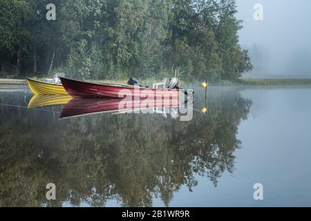 Deux bateaux amarrés au lac brumeux, lever du soleil tôt, arbres, reflet du ciel dans l'eau calme, belle scène relaxante, paysage européen, nature du nord Banque D'Images