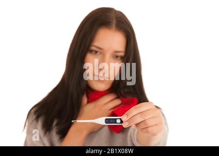 La femme malade a de la fièvre en vérifiant la température du corps avec un thermomètre isolé sur fond blanc Banque D'Images