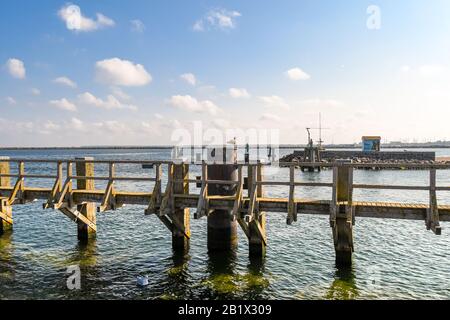 Une mouette se trouve au sommet d'un quai au port de croisière Warnemunde Rostock alors que le soleil descend sur la mer Baltique en Allemagne. Banque D'Images