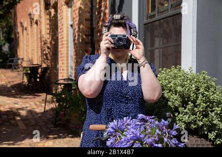 Jeune fille prenant des photos avec un appareil photo vintage sur vélo. Banque D'Images