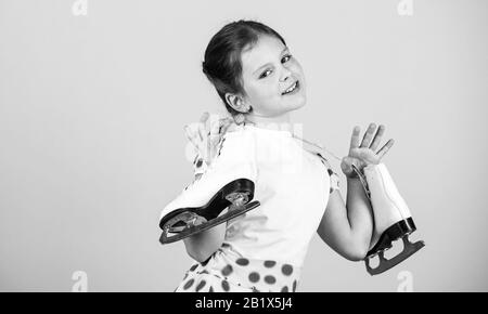 Vous permet d'aller patiner. Heureux l'enfant avec les patins accroché sur le cou. Petite fille profiter du patinage sur glace. Danse sur glace. Le patinage artistique. Piscine skatepark ou patinoire. Activités d'hiver. Jour de glace, copiez l'espace. Banque D'Images