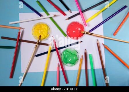 Feuille de papier blanche sur un fond bleu avec espace de copie et place pour s'inscrire autour d'un stylo couleur peinture, brosses et crayons copie espace. Brach Banque D'Images