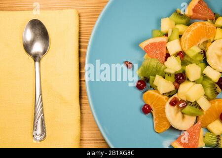 Salade de fruits frais sur une plaque bleue qui se tient sur une table en bois avec un endroit pour l'inscription. Salade d'agrumes avec espace publicitaire Banque D'Images
