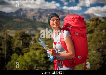 Joli randonneur féminin en haute montagne à l'aide d'une carte pour trouver un chemin à travers une chaîne de montagne Banque D'Images