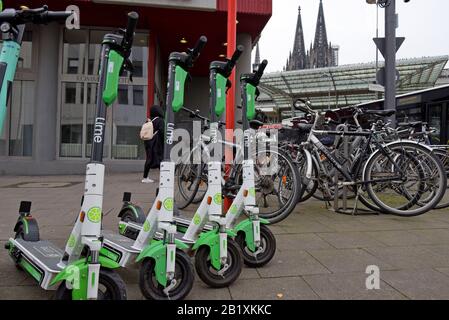 Une rangée de scooters de location électriques sans impuretés Lime S stationnés à côté d'un porte-vélos dans le centre de Cologne, en Allemagne Banque D'Images