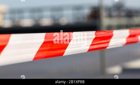 Gros plan de ruban en plastique rouge à rayures blanches. Utilisé pour arrêter les zones . E. g. sites de construction, scènes de crime, zones de danger. Arrière-plan flou. Banque D'Images