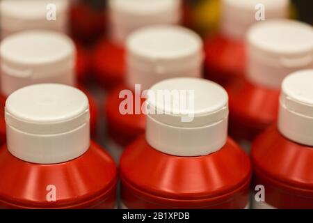 Gros plan / macro de bouteilles en plastique avec bouchon blanc et corps rouge. Les bouteilles contiennent du ketchup. Banque D'Images