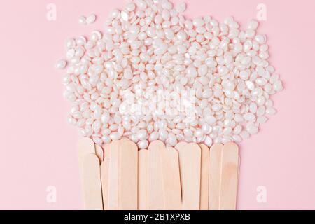 Cire pour l'épilation de la couleur blanche de perle et de la spatule en bois sur fond rose. Concept de cirage, peau lisse, soins du corps, secteur du spa. Interdiction Banque D'Images