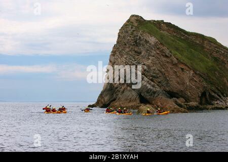 Entrée à Lulworth Cove, Dorset, Angleterre, Royaume-Uni: Les falaises de West point, avec les canoéistes passant une journée calme: Site classé au patrimoine mondial de l'UNESCO Banque D'Images