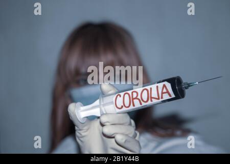 Vaccin contre le coronavirus. Médecin femme (flou) tenant la seringue et l'aiguille avec le virus corona écrit. Un spécialiste médical essaie de trouver un remède à la figue Banque D'Images