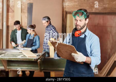 Carpenter avec une liste de contrôle sur un presse-papiers dans l'atelier Banque D'Images