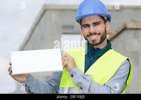 heureux constructeur de barbe en uniforme tenant une bannière blanche vide Banque D'Images