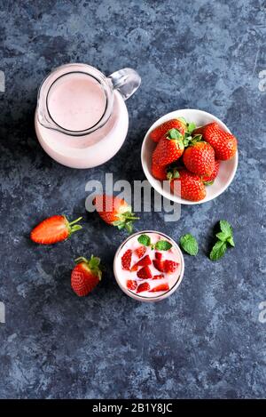 Yaourt à la fraise avec baies fraîches en verre sur fond de pierre bleue. Concept de nourriture et de boisson saine. Vue sur le dessus, plat Banque D'Images