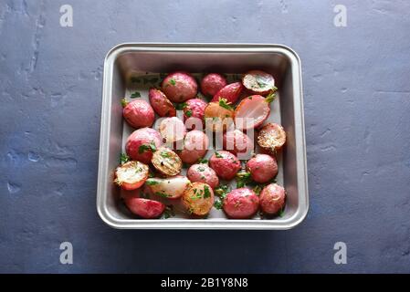 Raifort rôti dans la plaque de cuisson sur fond de pierre bleue. Cuisine végétalienne végétarienne. Vue rapprochée Banque D'Images