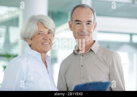 couple senior souriant avant la réunion à la maison Banque D'Images