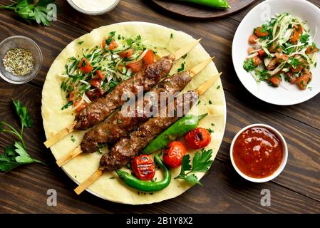 Adana Kebab turc avec des légumes frais sur pain plat sur fond de bois. Haut de la vue, télévision lay Banque D'Images