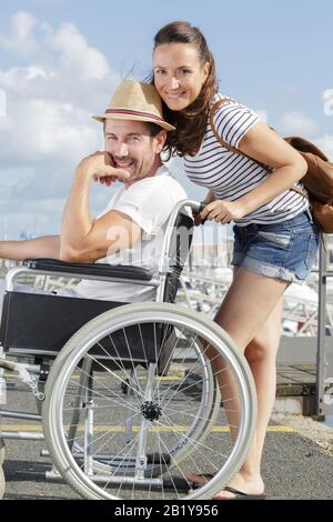 Couple aimant la marche à l'extérieur en fauteuil roulant Banque D'Images