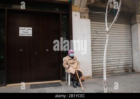 Beyrouth, Liban. 28 février 2020: Une femme assise à l'extérieur d'une salle de prière féminine à Beyrouth portant un masque protecteur contre le coronavirus covid 19. Le ministère des transports a annoncé que le Liban a interrompu les vols pour les non-résidents en provenance de pays aux épidémies de coronavirus, dont la Chine, l'Iran, l'Italie et la Corée du Sud. Crédit: Amer ghazzal/Alay Live News Banque D'Images