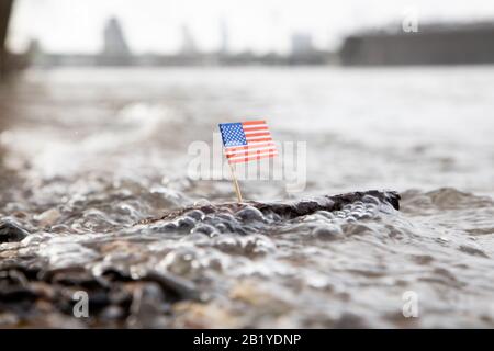 Drapeau des États-Unis coincé dans un morceau de bois flottant sur la mer rugueuse Banque D'Images