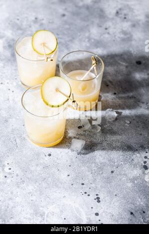 Un petit verre de mocktail ou de cocktail rafraîchissant à base de soda de poire sur fond gris en béton avec ombre. Boisson estivale sans alcool Banque D'Images