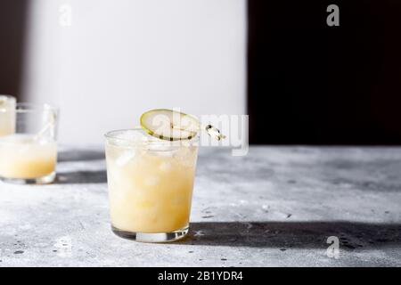 Un petit verre de mocktail ou de cocktail rafraîchissant à base de soda de poire sur fond de béton gris. Boisson estivale sans alcool. Orientation horizontale Banque D'Images