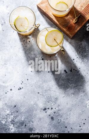 Un petit verre de mocktail ou de cocktail rafraîchissant à base de soda de poire sur fond de béton gris. Boisson estivale sans alcool. Orientation verticale Banque D'Images