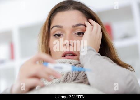 femme malade avec fièvre de vérifier sa température avec un thermomètre Banque D'Images