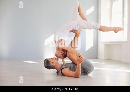 Un couple de yoga pratique le yoga acro sur le sol dans un cours de studio. Banque D'Images